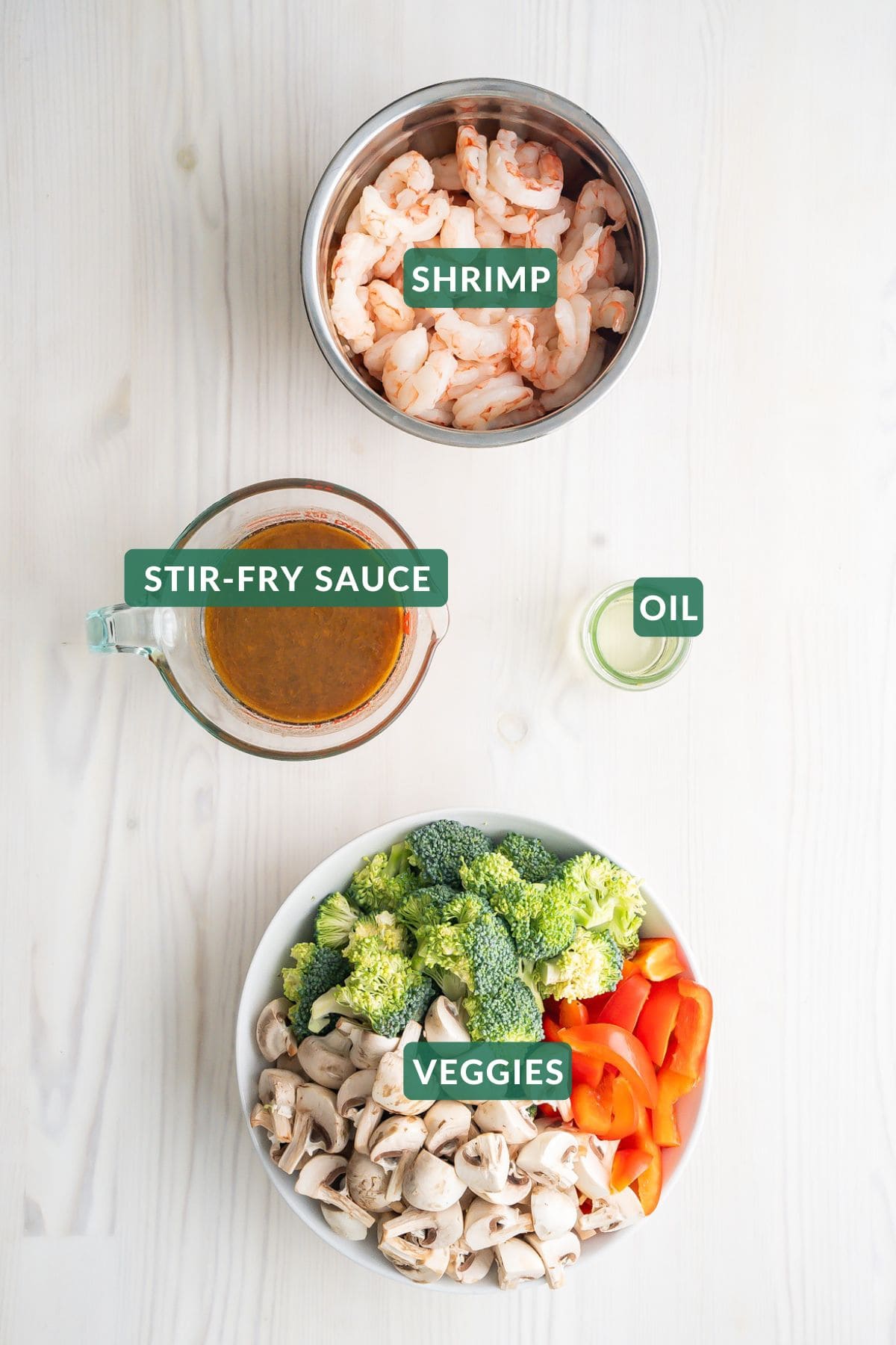 The four ingredients needed to make a shrimp stir-fry: shrimp, stir-fry sauce, oil, and vegetables.