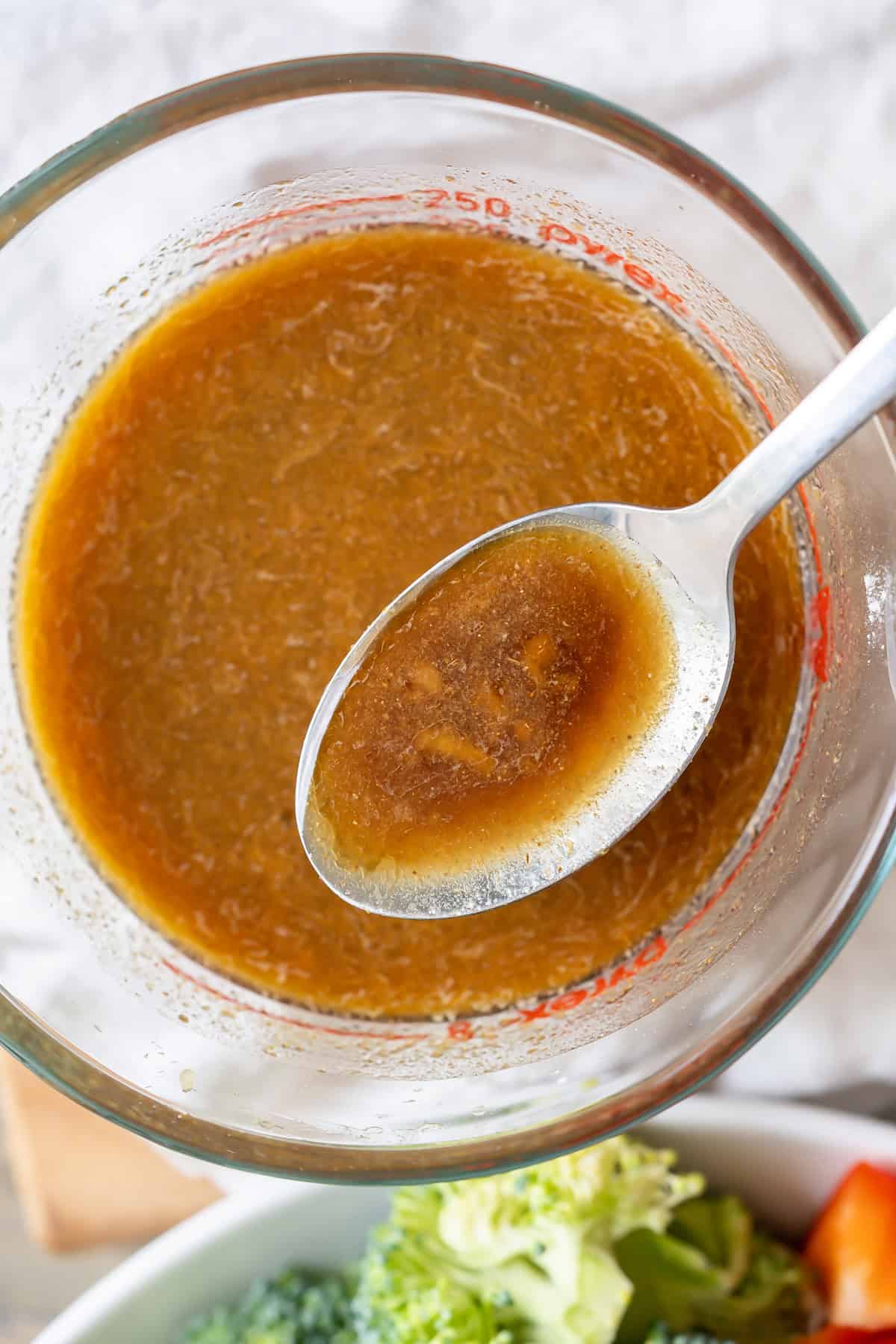 A spoonful of stir-fry sauce with pieces of garlic and ginger.