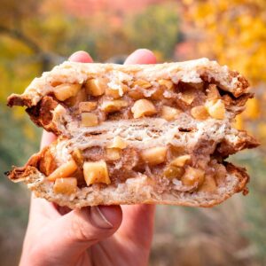 A campfire pie iron apple pie split in half to show the crispy outer "crust" and apple filling.