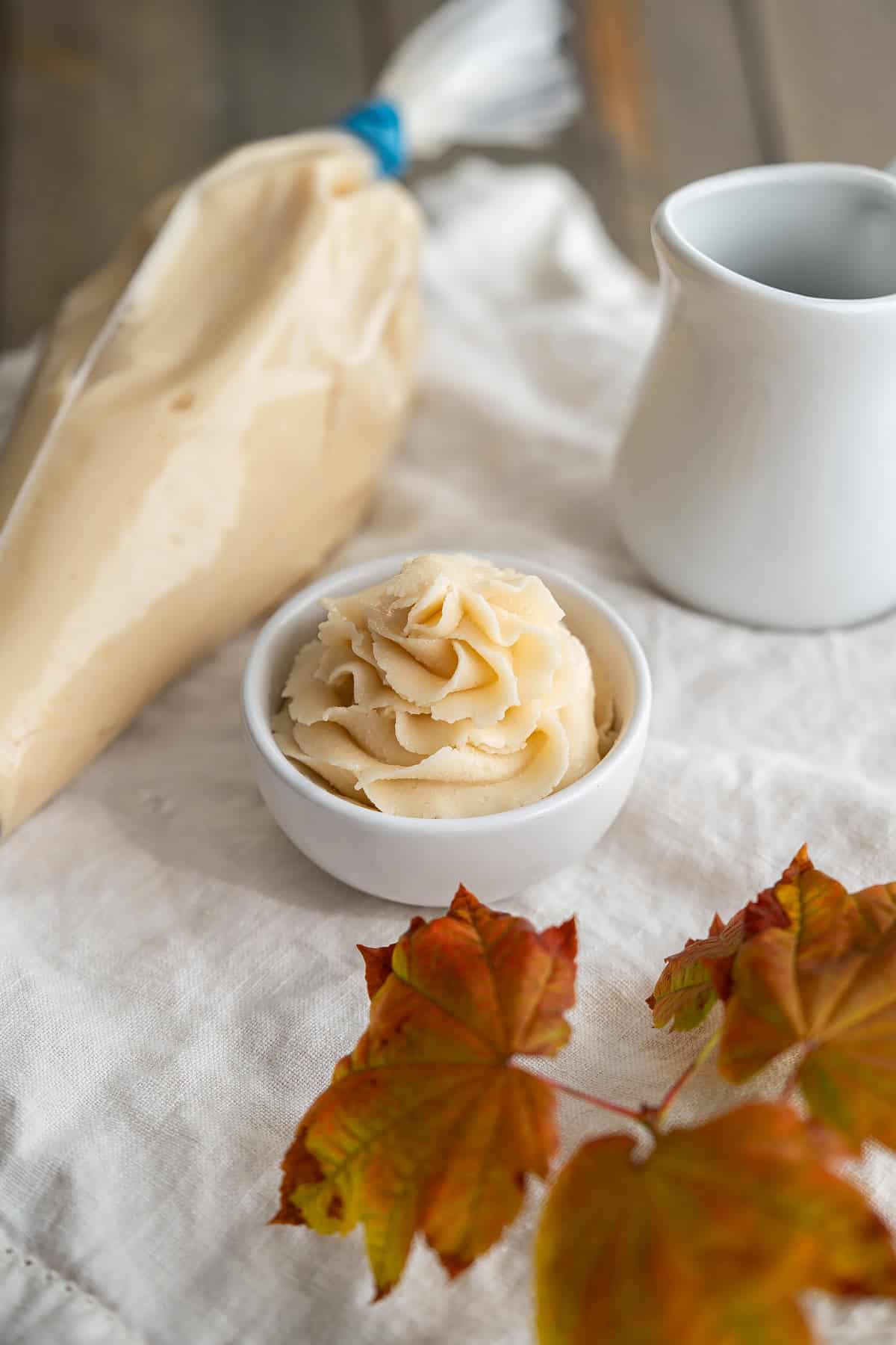 A piping bag and piped maple buttercream rose.