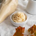 A piping bag and piped maple buttercream rose.