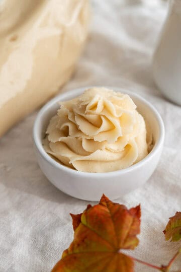 A piping bag and piped maple buttercream rose.