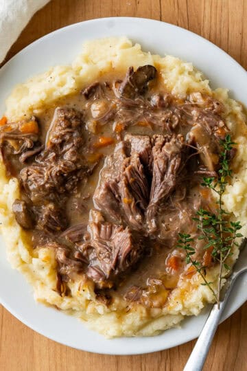 A serving of instant pot short ribs over garlic mashed potatoes.