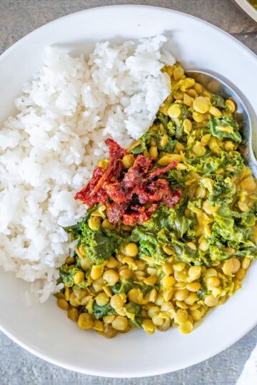 Kale lentil curry with rice and garnished with sun-dried tomatoes.
