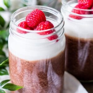 A jar of mocha chia pudding topped with whipped cream and berries.