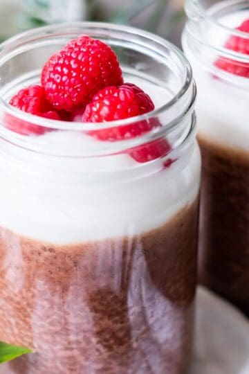 A jar of mocha chia pudding topped with whipped cream and berries.