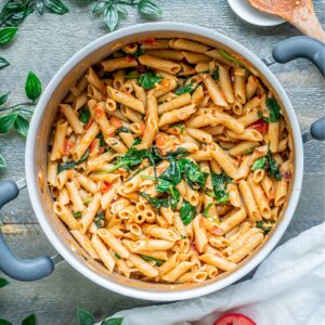 A pot of lentil pasta with tomatoes and basil.