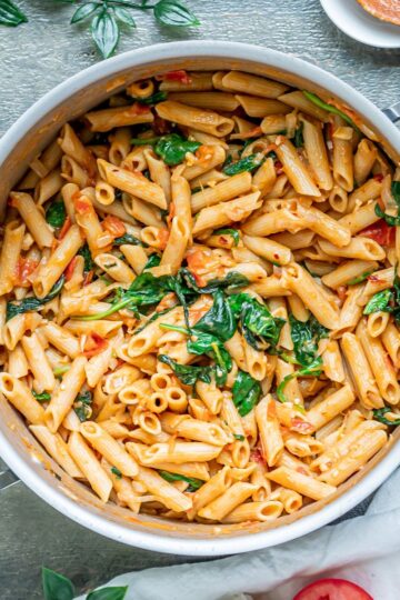 A pot of lentil pasta with tomatoes and basil.