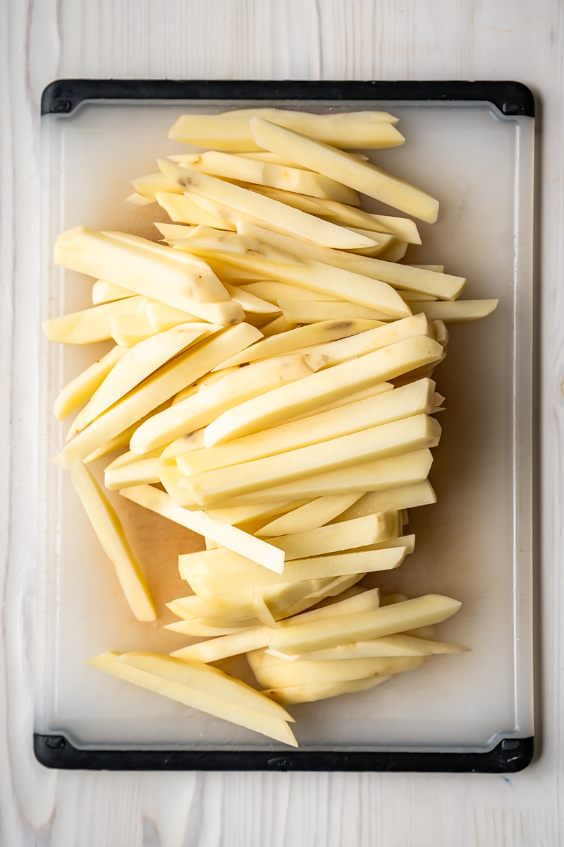 A pile of potatoes cut into a fry shape.