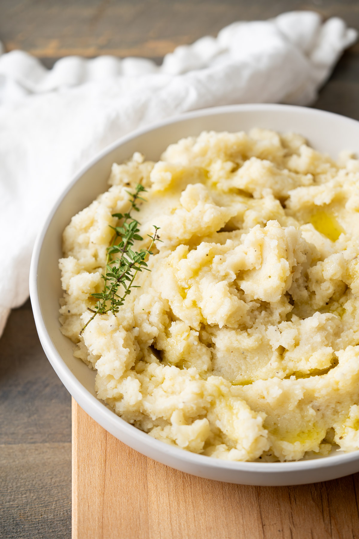 Fluffy dairy-free mashed potatoes drizzled with olive oil and garnished with thyme.